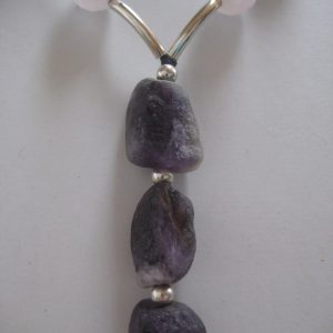 Zoom auf den langen Anhänger aus violetten Amethysten und die silbernen Zwischenstücke einer Edelsteinkette aus Amethyst, Bergkristall und Rosenquarz.
