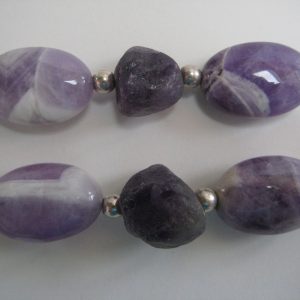 Zoom auf einzelne Steine einer Edelsteinkette aus Amethyst, Bergkristall und Rosenquarz in Lila- und Rosétönen.