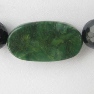 Zoom auf den grünen ovalen Jadestein einer Edelsteinkette aus Jade, Serpentin und Turmalin.