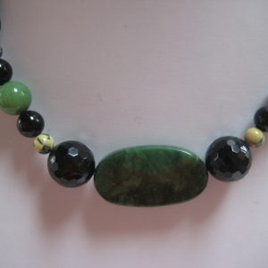 Zoom den grünen Jadestein einer Edelsteinkette aus Jade, Serpentin und Turmalin.