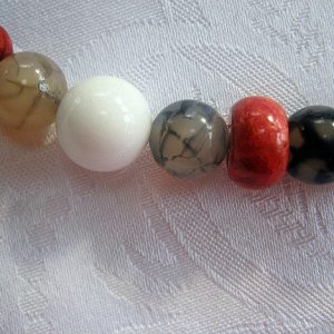 Zoom auf einen weißen Jadestein, grauen Spinnenachat und rote Schaumkoralle Edelsteinkette aus Koralle, Jade und Achat.