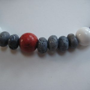 Nahaufnahme von einzelnen Steinen einer Edelsteinkette aus Koralle und Jade mit roten, blauen und weißen Edelsteinen.