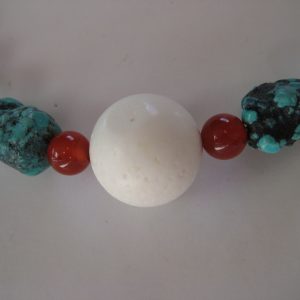 Zoom auf die mittige weiße Korallenkugel Edelsteinkette aus Türkis, Rosenquarz, Karneol, und Onyx.