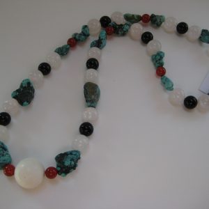 Aufgelegte Edelsteinkette aus Türkis, Rosenquarz, Karneol, und Onyx. Die Steine sind weiß, schwarz, rot, und türkis.