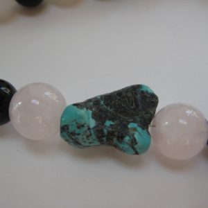 Zoom auf einen Türkis der Edelsteinkette aus Türkis, Rosenquarz, Karneol, und Onyx.